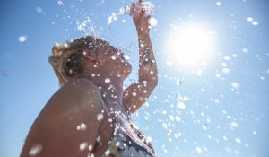 A young woman cools down with cold water during the summer heat.