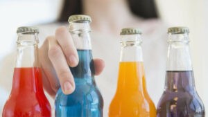 Young woman reaching for colorful bottles of soda