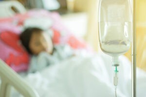 saline solution and child patient asleep on bed at hospital